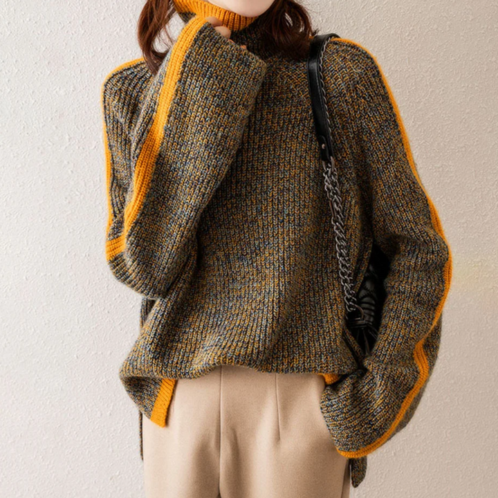 Frau in grauem Strickpullover mit gelben Streifen, beige Hose, schwarze Tasche.