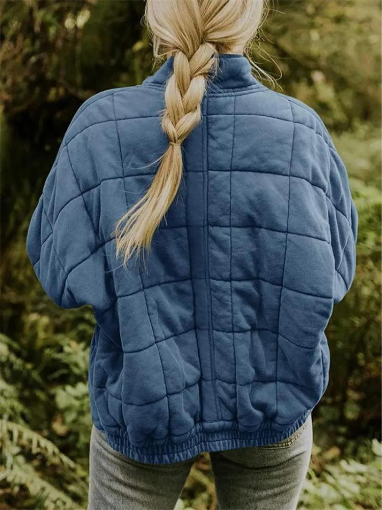 Frau in blauer, gesteppter Übergangsjacke im Wald, Rückansicht, Herbstmode.