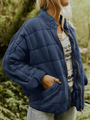 Frau in blauer, gesteppter Übergangsjacke, oversized, mit Reißverschluss, im Freien.