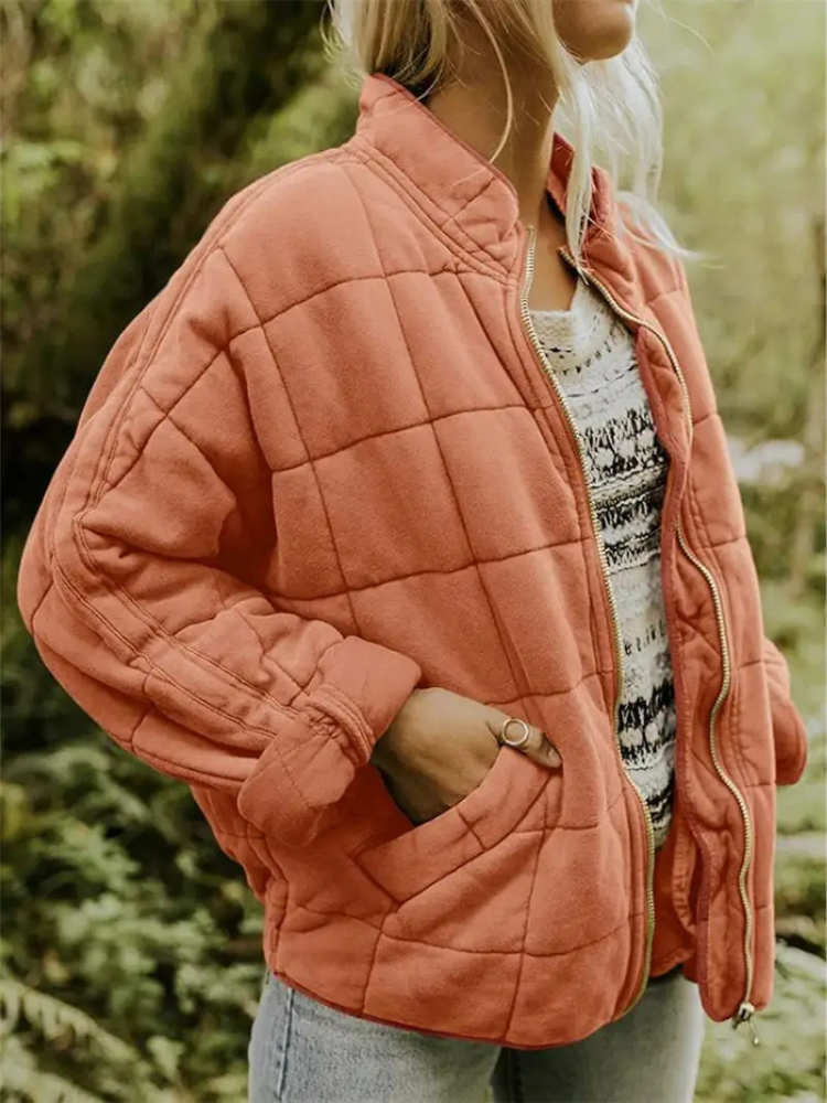 Frau in orangefarbener, gesteppter Übergangsjacke im Freien.