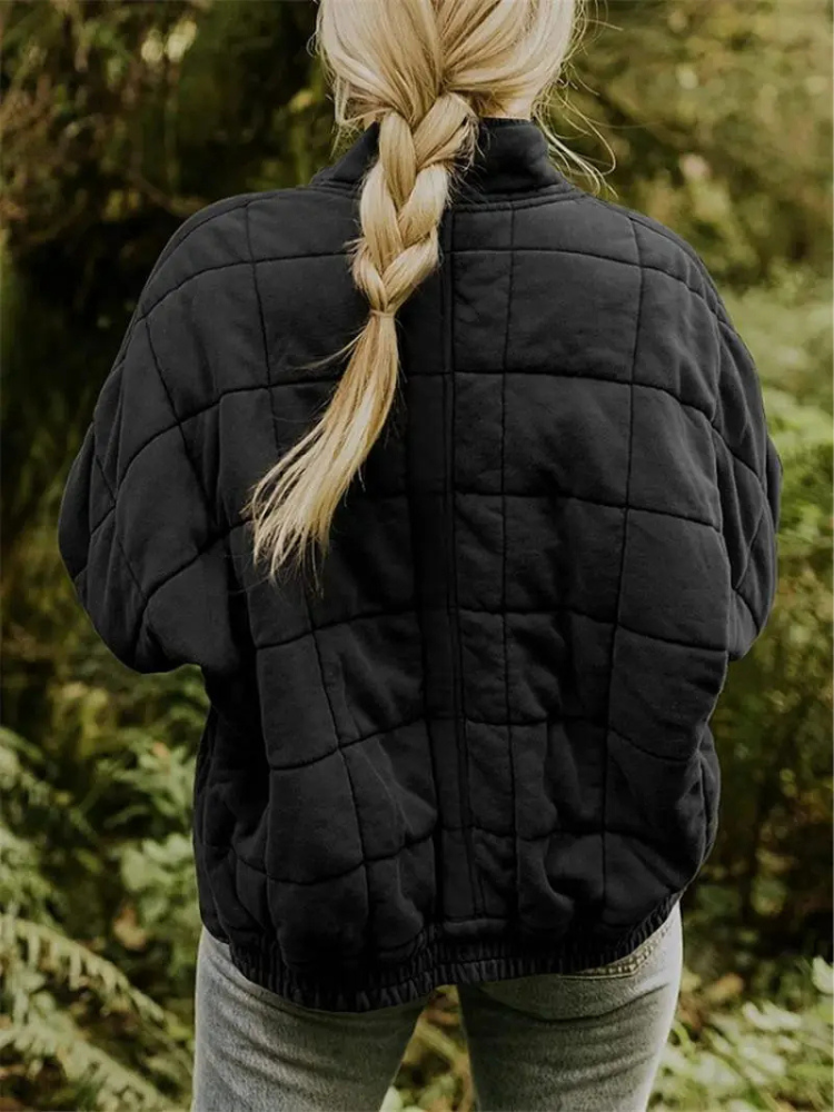 Blonde Frau in schwarzer, gesteppter Übergangsjacke im Wald, Herbstmode, Damenbekleidung.