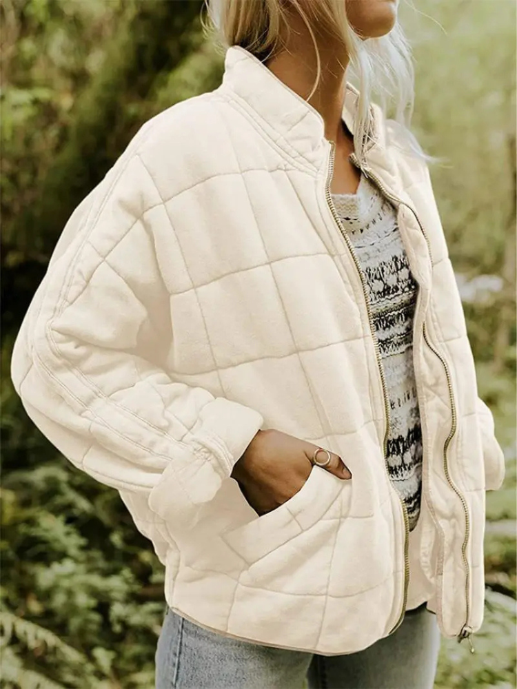Frau in cremefarbener, gesteppter Übergangsjacke, oversized, mit Reißverschluss, Herbstmode.