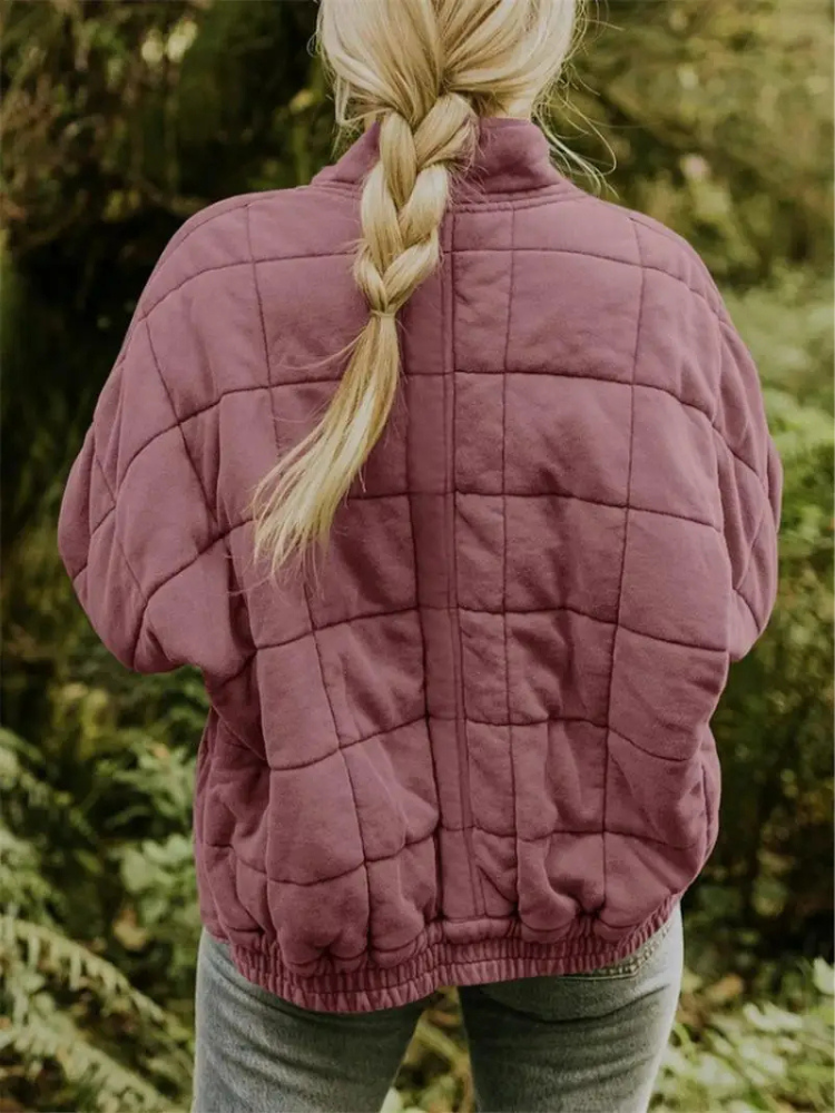 Frau in lila Steppjacke, oversized, Übergangsjacke, Herbstmode, draußen im Wald.