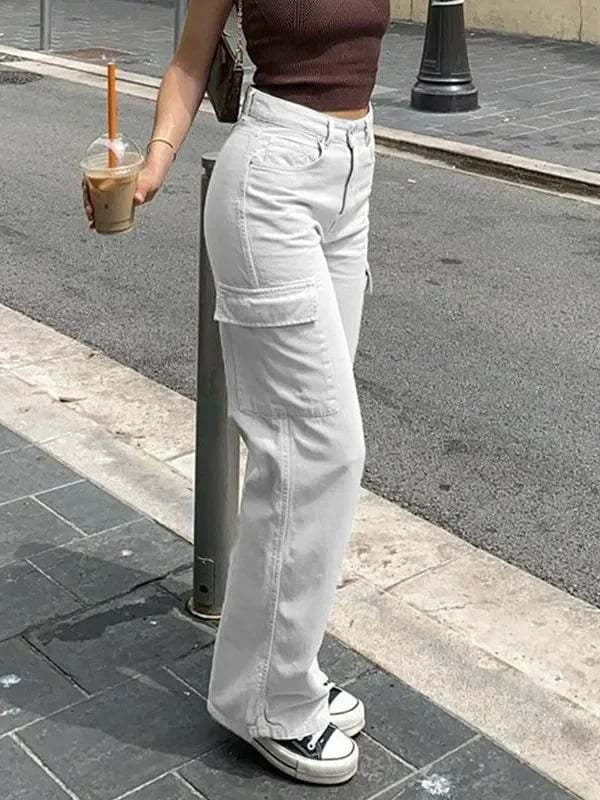 Frau in weißen Cargo-Hosen und braunem Top mit Eiskaffee auf Gehweg.