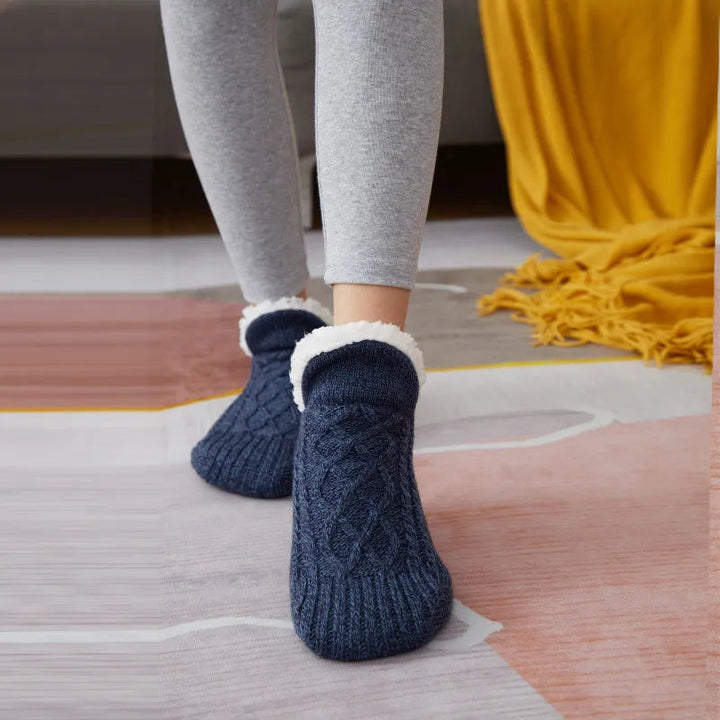 Dunkelblaue Stricksocken mit Fleece-Futter, gemütlich, warm, auf Teppichboden, graue Leggings.