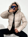 Frau in beiger Daunenjacke mit Kapuze, schwarze Sonnenbrille, Smartphone, modisch, Winterkleidung.