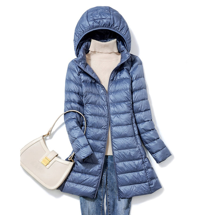 Blaue Daunenjacke mit Kapuze, Damenmode, Wintermantel, beige Handtasche, Jeans, Pullover.