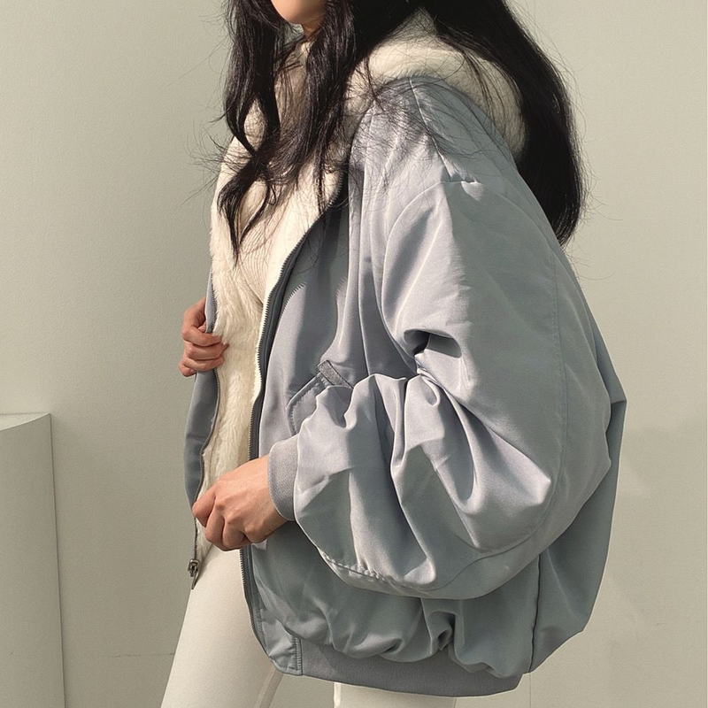 Frau in grauer Bomberjacke mit weißem Fellfutter, modisch, lässig, Winterkleidung.