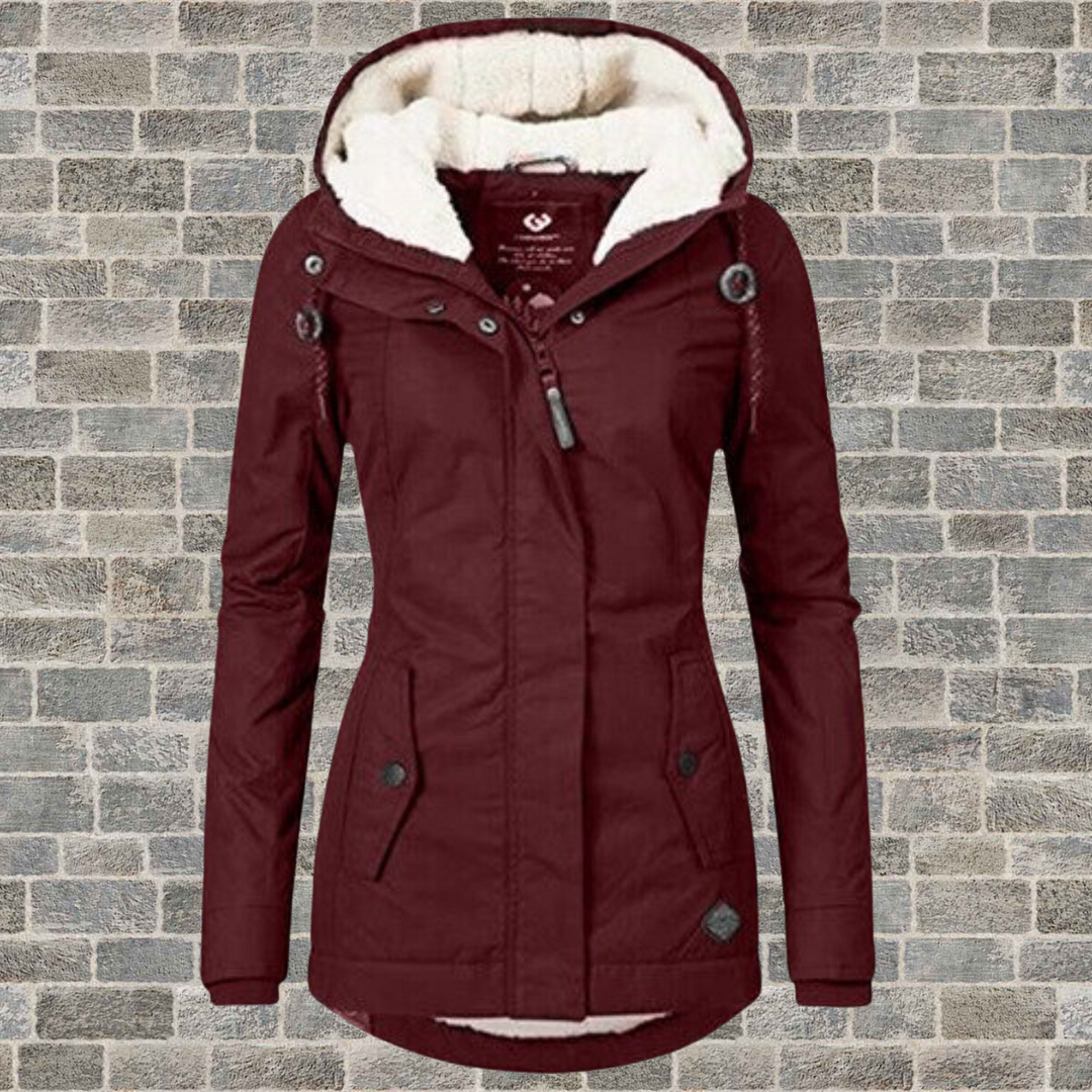 Bordeaux Damen Winterjacke mit Kapuze, Fleece-Futter, warm, modisch, vor Ziegelwand.