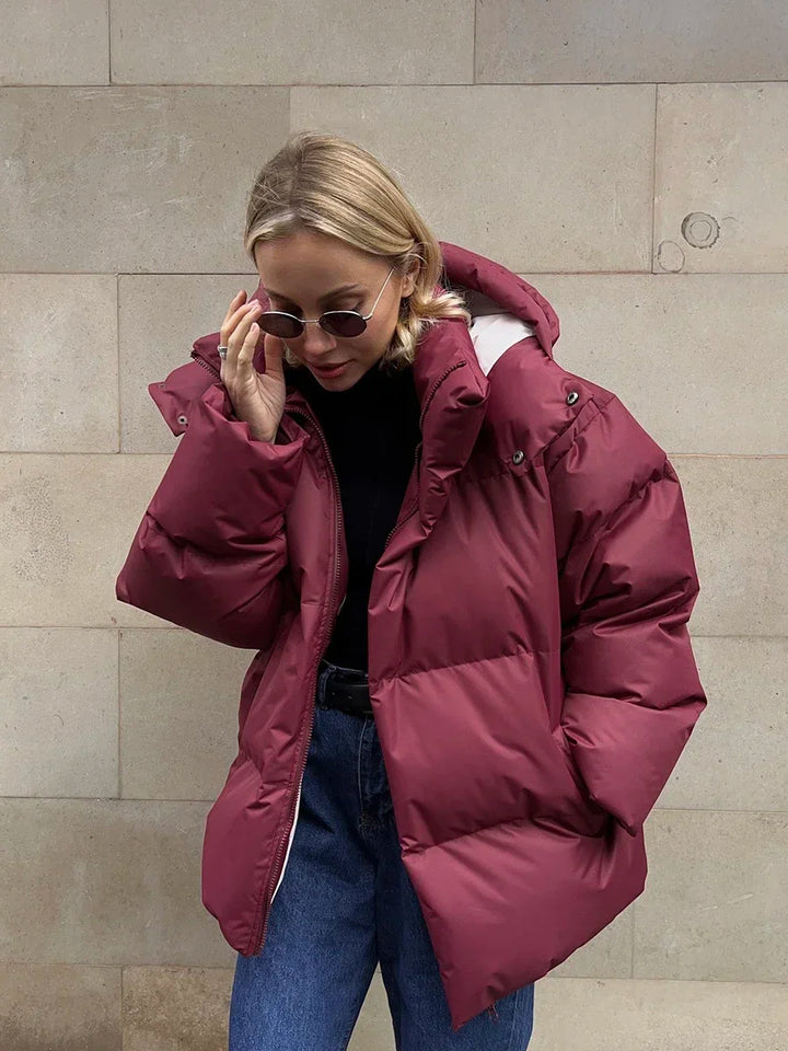Frau in roter Daunenjacke, Sonnenbrille, Jeans, Wintermode, Outdoor-Bekleidung.