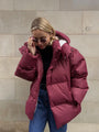Frau in roter Daunenjacke, Sonnenbrille, Jeans, Wintermode, Outdoor-Bekleidung.