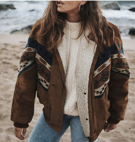 Frau in brauner Wildlederjacke mit Ethno-Muster am Strand, lässiger Herbstlook.