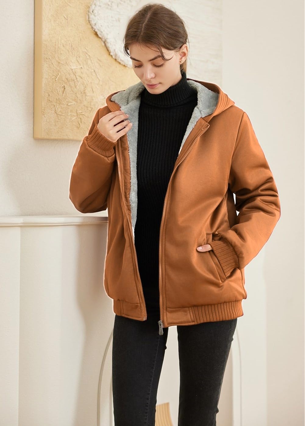 Frau in brauner Fleecejacke mit Kapuze, schwarzer Rollkragenpullover, lässige Wintermode.