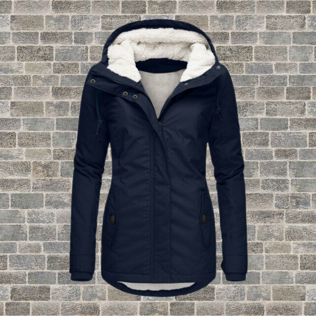 Damen Winterjacke mit Kapuze, dunkelblau, gefüttert, vor Ziegelwand, modisch und warm.