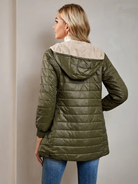 Frau in olivgrüner Steppjacke mit Kapuze, Rückansicht, modische Herbstbekleidung.