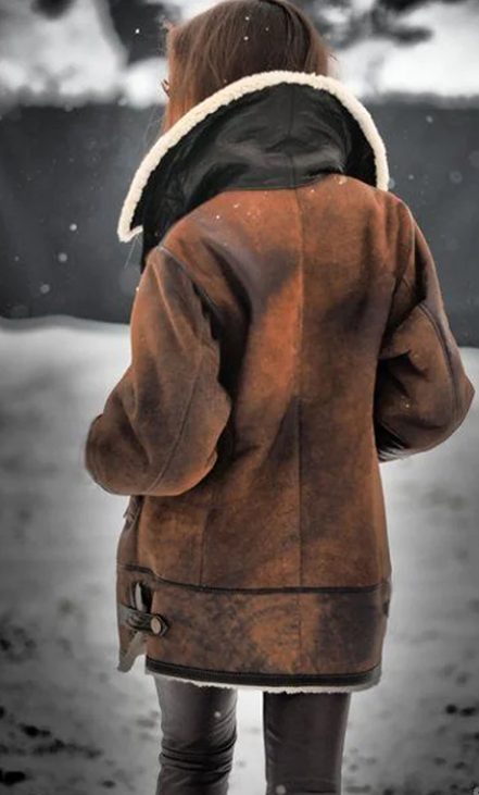 Frau in brauner Lederjacke mit Fellkragen im Schnee, Wintermode, stilvoll, warm, Outdoor-Bekleidung.