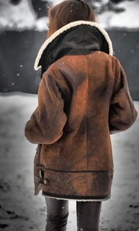 Frau in brauner Lederjacke mit Fellkragen im Schnee, Wintermode, stilvoll, warm, Outdoor-Bekleidung.