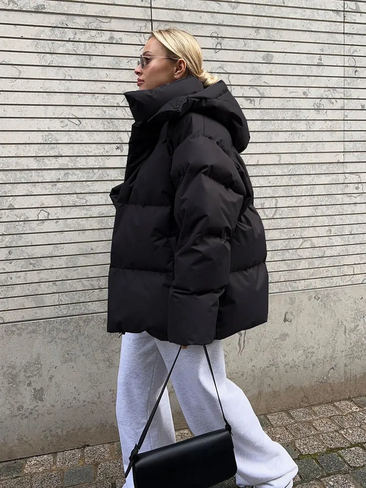 Frau in schwarzer Daunenjacke, weiße Jogginghose, schwarze Tasche, Wintermode, Straßenstil.
