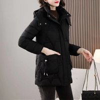 Frau in schwarzer Daunenjacke mit Kapuze, hält eine gesteppte Handtasche, Wintermode.