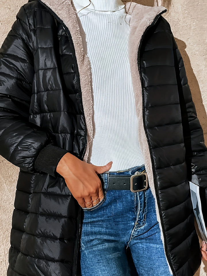 Frau in schwarzem Steppmantel, weißem Rollkragenpullover und blauer Jeans, modischer Winterlook.