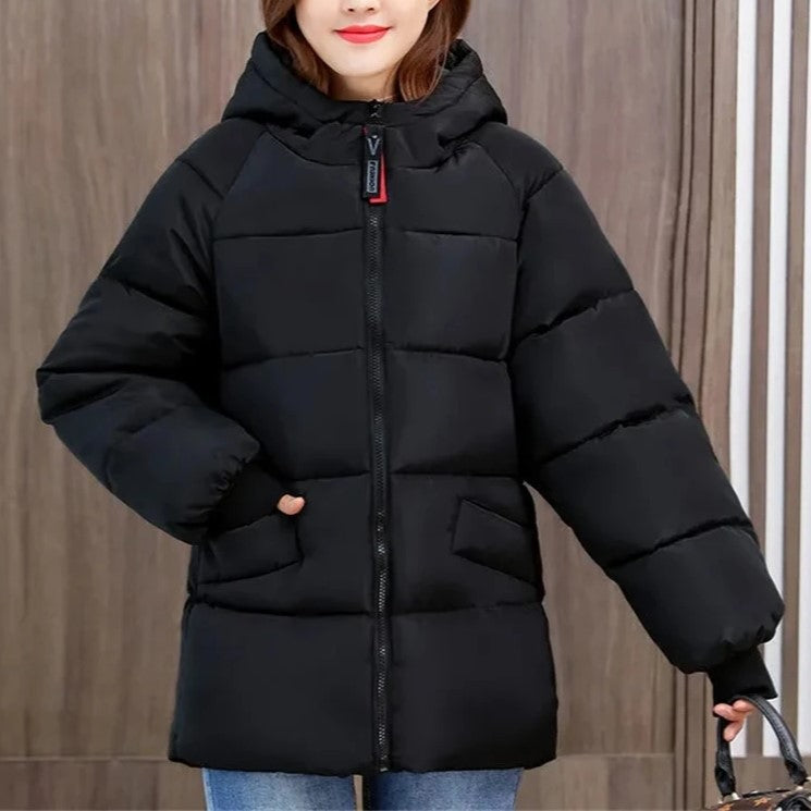 Frau in schwarzer Daunenjacke mit Kapuze, Wintermode, warm, stilvoll, Outdoor-Bekleidung.