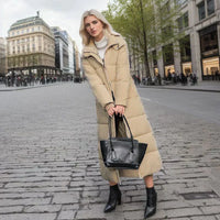 Frau in beigem Daunenmantel mit schwarzer Handtasche auf städtischer Straße im Frühling.