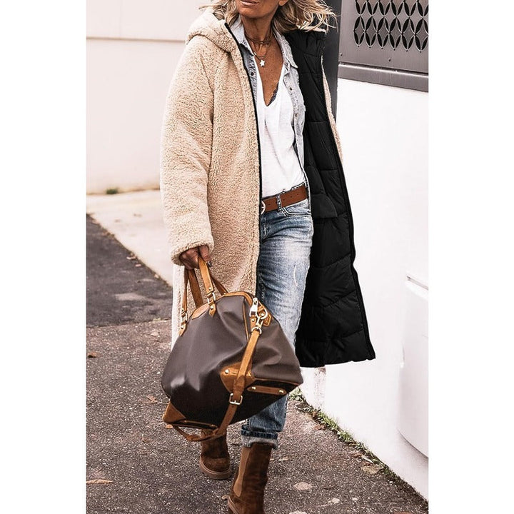 Frau in beigem Teddy-Mantel, Jeans und braunen Stiefeln mit brauner Ledertasche auf Straße.