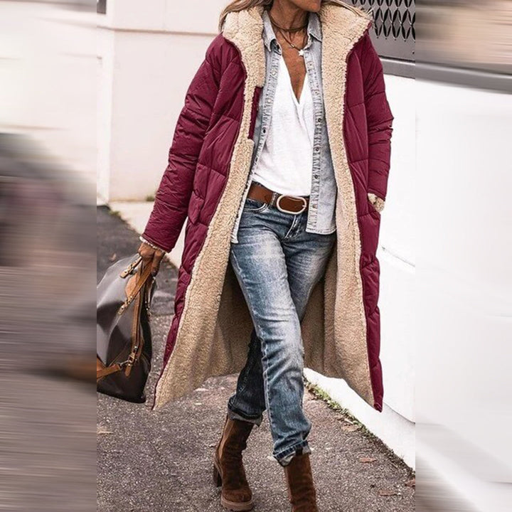 Frau in rotem Wintermantel mit Fellfutter, Jeans und Stiefeln, modischer Winterlook.