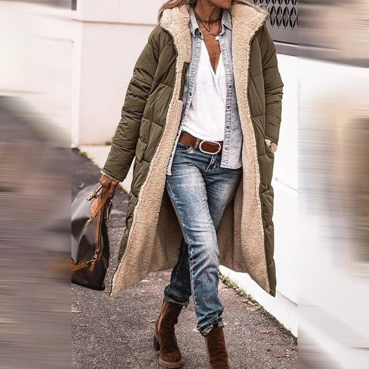 Frau in olivgrünem Wintermantel mit Fellfutter, Jeans und Stiefeln auf der Straße.