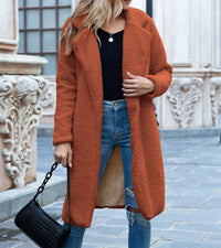 Frau in orangefarbener Winterjacke, Jeans, schwarze Tasche, Stadtumgebung.