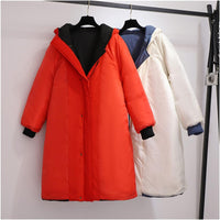 Zwei lange Wintermäntel, rot und weiß, mit Kapuze, auf Kleiderbügeln hängend.