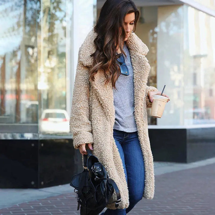 Frau in beiger Teddyfellmantel, Jeans, grauem Shirt, mit schwarzer Tasche und Kaffee, Stadtstraße.