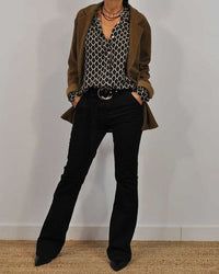 Frau in braunem Blazer, gemusterter Bluse und schwarzer Hose, modisches Outfit, Herbstmode.