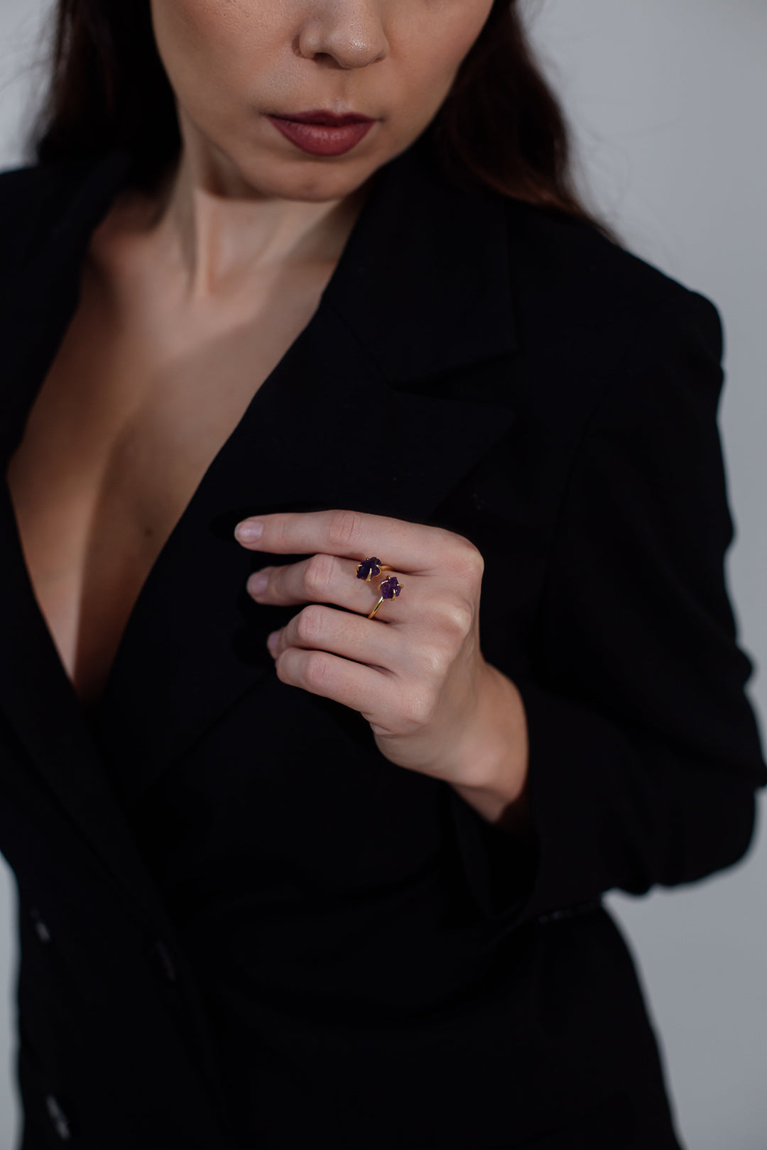 Frau in schwarzem Blazer mit lila Edelsteinring, eleganter Schmuck, Modeaccessoire.