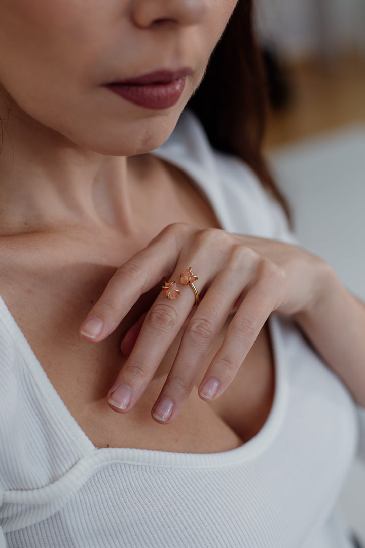Frau trägt goldenen Ring mit rosa Edelstein, Nahaufnahme, elegante Schmuckmode.