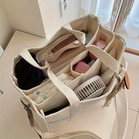 Beige Canvas-Tasche mit Fächern, gefüllt mit Alltagsgegenständen, ideal für Organisation und Reisen.