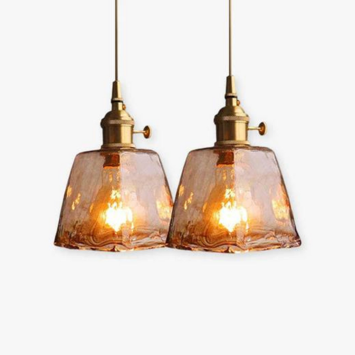 Zwei hängende Glas-Pendelleuchten, Vintage-Stil, warmes Licht, goldene Fassung.