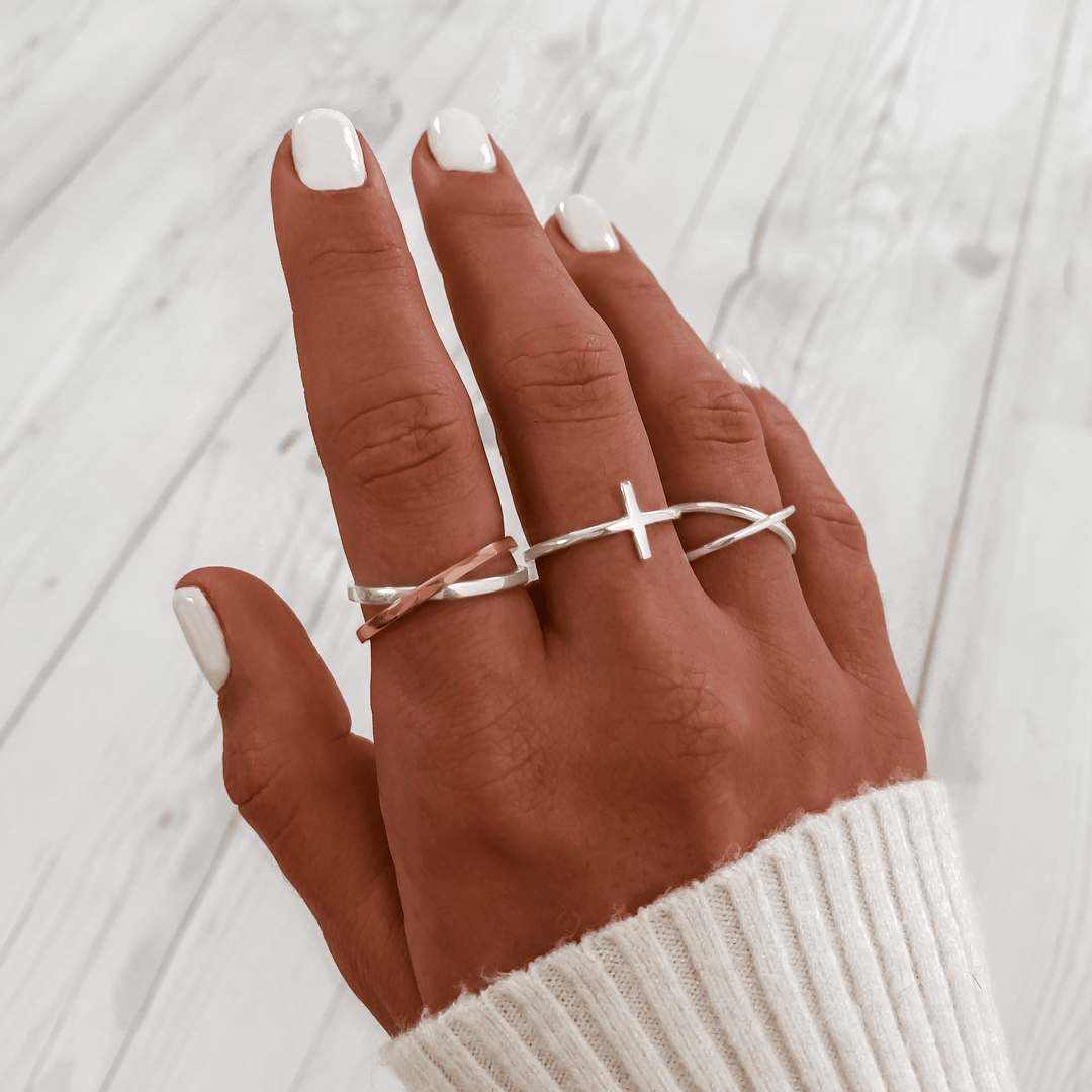 Silberne Kreuzringe an Hand, minimalistischer Schmuck, Damenmode, stilvoll, modern.