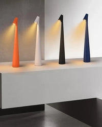 Vier moderne LED-Tischlampen in Orange, Weiß, Schwarz und Blau auf weißem Tisch.