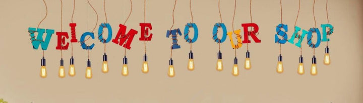 Bunte Buchstaben "Welcome to Our Shop" mit hängenden Glühbirnen, Dekoration, Geschäftseingang.