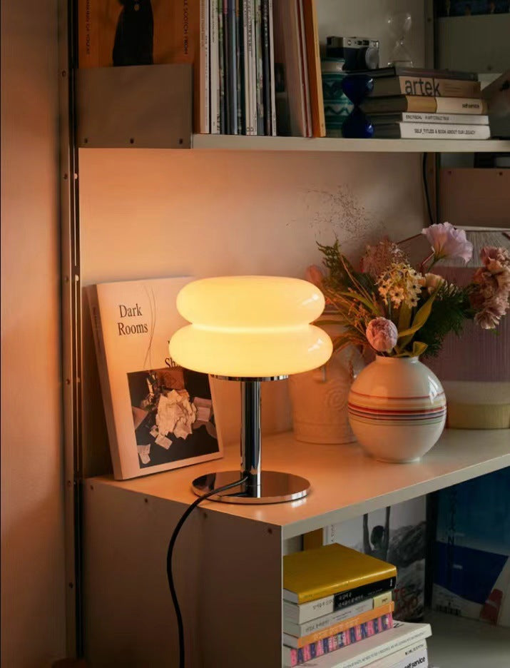 Retro Tischlampe aus Glas, leuchtend, auf Regal mit Büchern und Vase, Wohnzimmer-Dekoration.