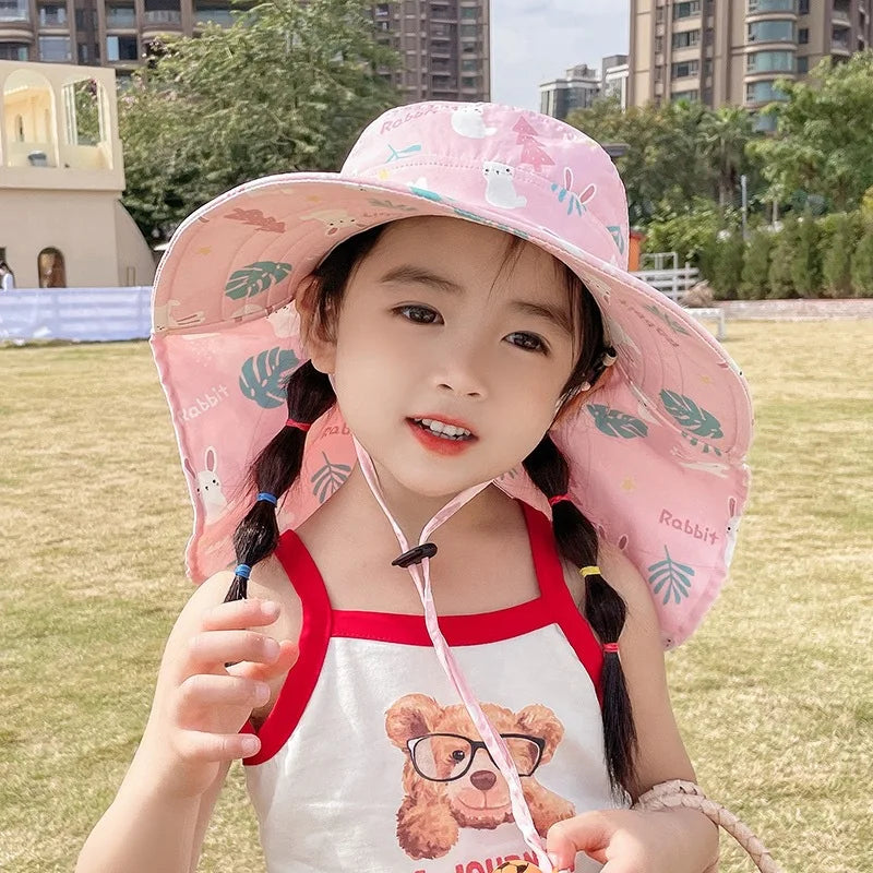 Mädchen mit rosa Sonnenhut, Kaninchenmuster, Sommerkleidung, draußen, Stadtpark.