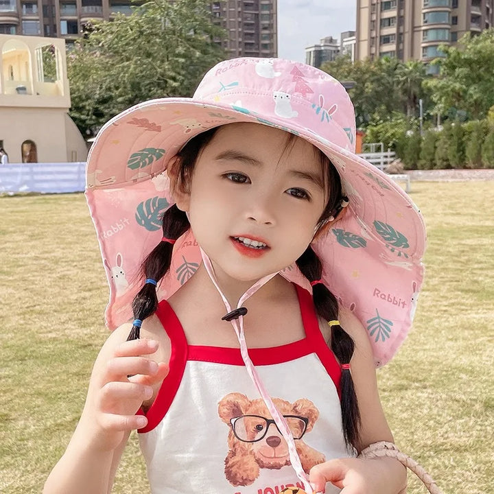 Mädchen mit rosa Sonnenhut, Kaninchenmuster, Sommerkleidung, draußen, Stadtpark.