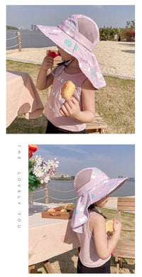 Ein Kind mit lila Sonnenhut und rosa Top isst ein Eis im Freien.