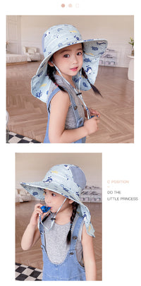 Mädchen mit blauem Sonnenhut und Latzhose im Innenraum, lächelnd, modisch, Kinderkleidung.