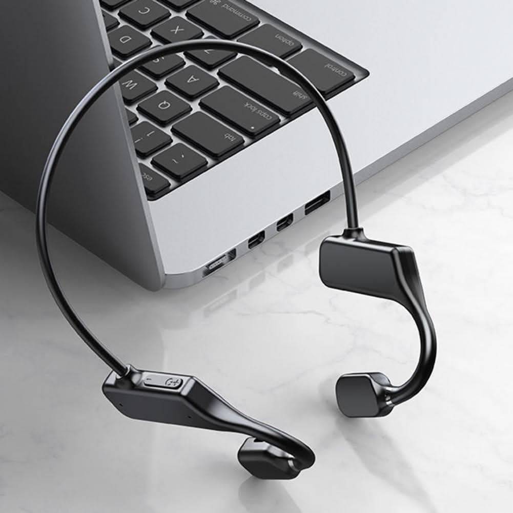 Drahtlose Knochenleitungs-Kopfhörer schwarz, neben Laptop, modernes Design.