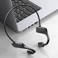 Drahtlose Knochenleitungs-Kopfhörer schwarz, neben Laptop, modernes Design.