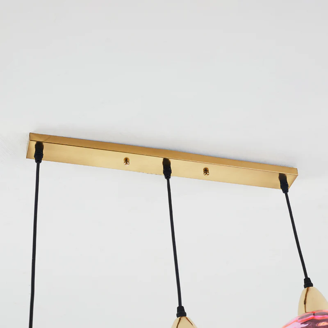 Goldene Deckenleuchte mit drei schwarzen Kabeln, modernes Design, minimalistische Beleuchtung.