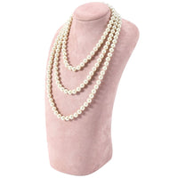 Perlenkette auf rosa Samtständer, eleganter Schmuck, dreireihig, klassisches Design.