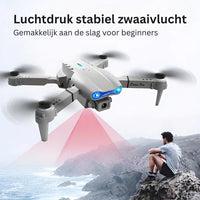 Graue Drohne mit Kamera, LED-Leuchten, faltbar, ideal für Anfänger, fliegt über Küste.